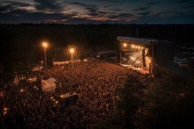 Festivalscen med publik och flaggor i sommarsolen