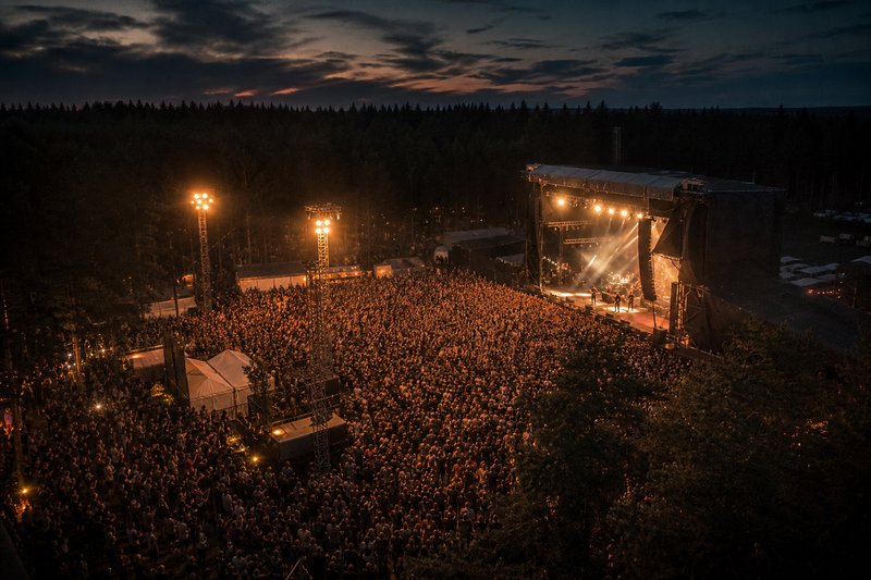 Festivalscen med publik och färgglada ljussättningar under en sommarnatt